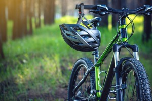Sports helmet on a green mountain bike in the Park among the trees. Concept protection during active and healthy lifestyle